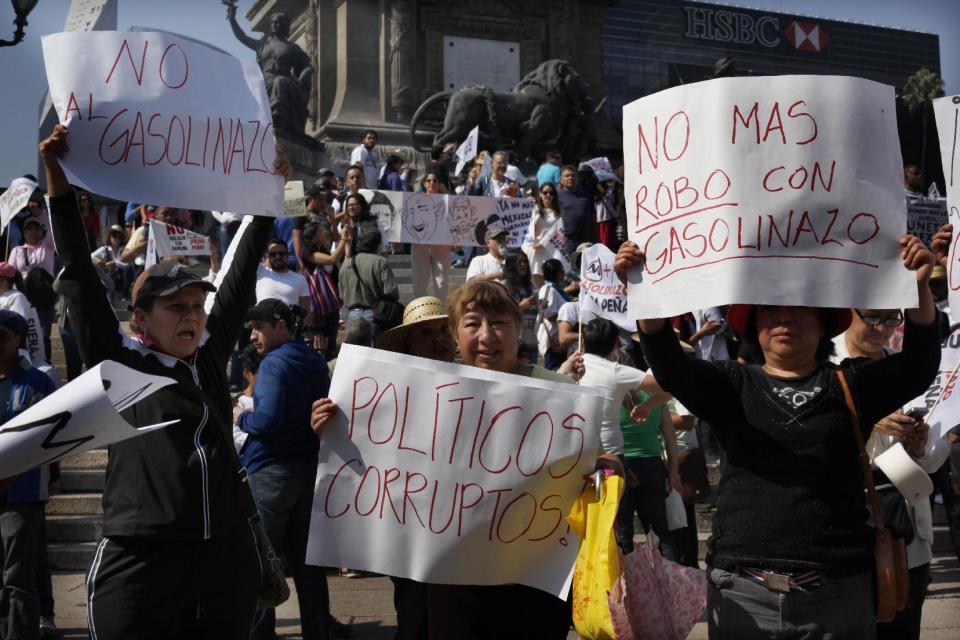 Protesters hold sings against fuel price hikes, that read in Spanish "No more gasoline price hike," "Corrupt Politicians" and "No more stealing with gasoline price hikes," in Mexico City, Saturday, Jan. 7, 2017. Sometimes-violent protests and looting over gasoline price hikes in Mexico are continuing and officials say that so far they've left one policeman dead and five injured, 300 stores looted and over 600 people arrested. (AP Photo/Marco Ugarte)