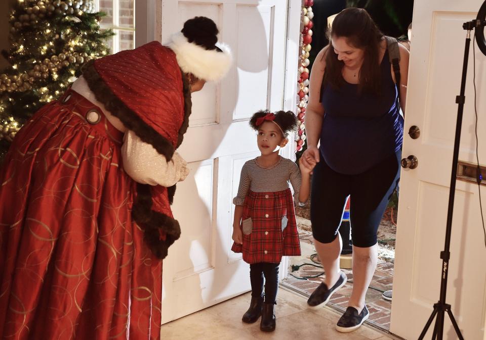 Mrs. Claus, also known as Natasha Spencer-Coley greets 3-year-old Laila Williams and her mother Grace as they arrive for a meeting with Santa and Mrs. Claus.