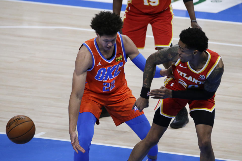 Atlanta Hawks forward John Collins (20) passes the ball away from Oklahoma City Thunder center Isaiah Roby (22) during the first half of an NBA basketball game Friday, Feb. 26, 2021, in Oklahoma City. (AP Photo/Garett Fisbeck)