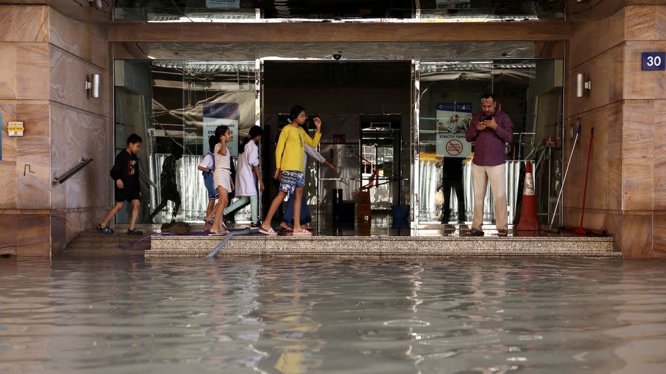 People stand as flood water caused by heavy rains covers the stairs of a residential building, in Dubai, United Arab Emirates on Wednesday. - Amr Alfiky/Reuters