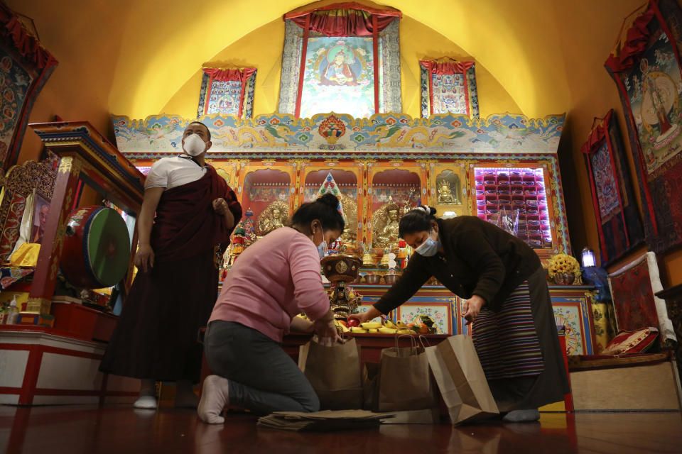 Lama Gelbu, left, Pasang Sherpa, center, and Yanddu Lama, right, prepare bags of fruit used as ceremonial offerings at the conclusion of the Dakini Day practice, a group meditation that includes song and food and is celebrated on the 25th day of each lunar month, at the United Sherpa Association in the Queens borough of New York on Friday, Jan. 8, 2021. (AP Photo/Jessie Wardarski)