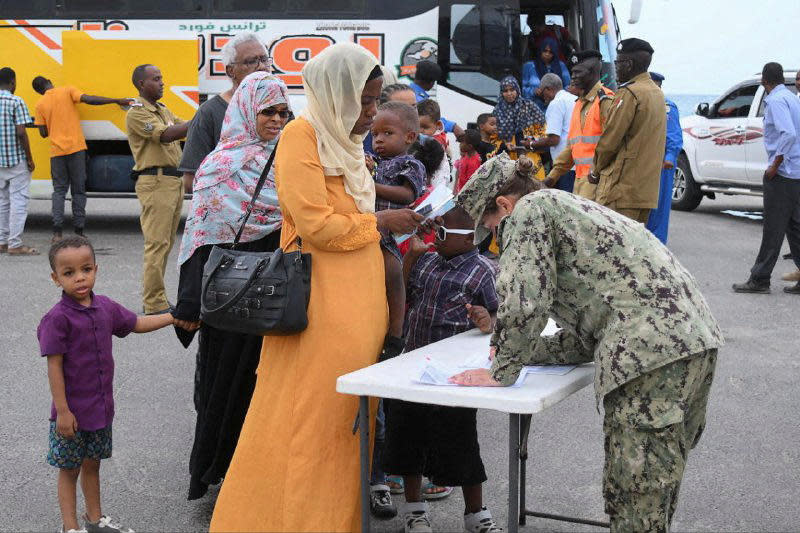 U.S. nationals arrive for evacuation from the port, amid ongoing clashes between the paramilitary Rapid Support Forces and the Sudanese army, in Port Sudan, Sudan, April 30, 2023. Zienab Abaker is seen at the table in yellow, with her sons next to her. / Credit: STRINGER/REUTERS