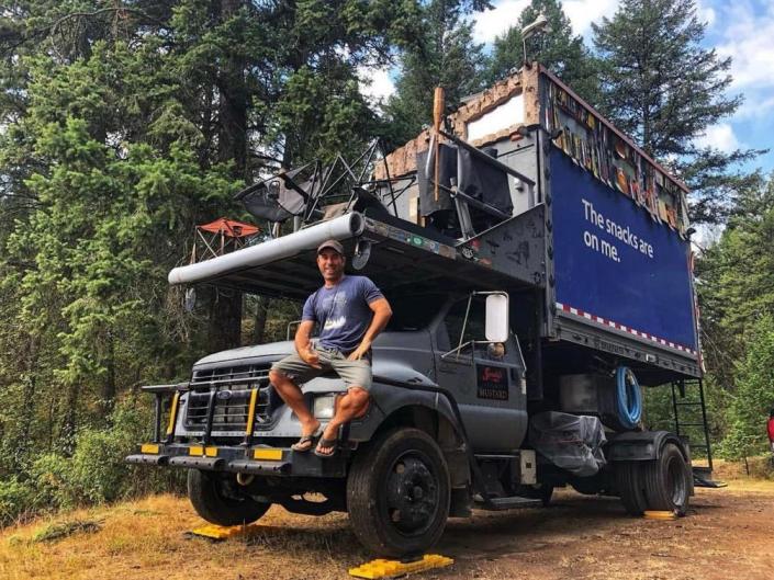 Mark Pankey sitting on the hood of his converted aircraft box truck tiny home.