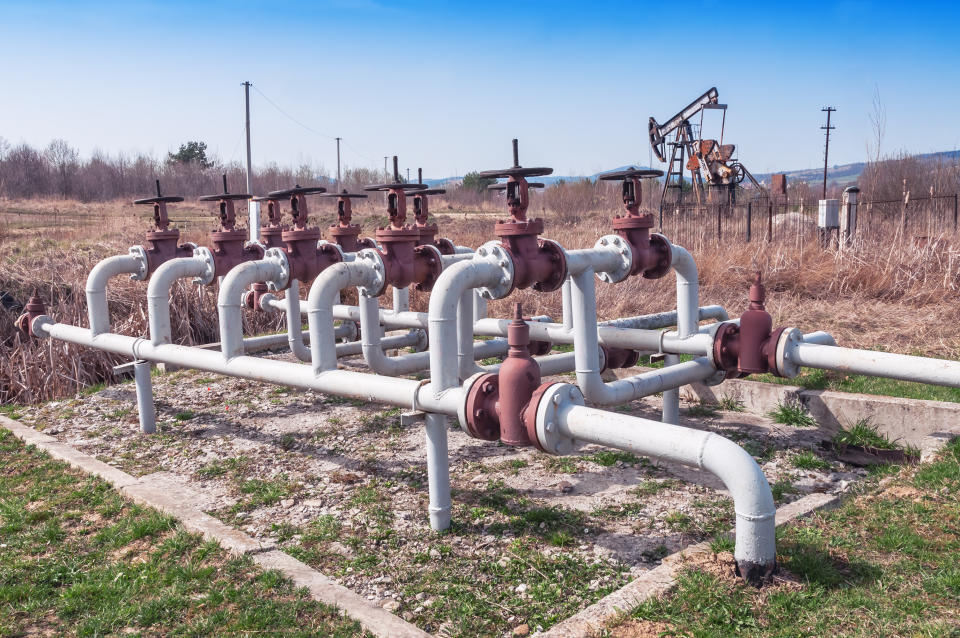 Pipeline valves with an oil pump in the background.