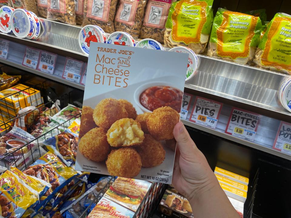 hand holding box of mac and cheese bites in the freezer aisle at trader joes