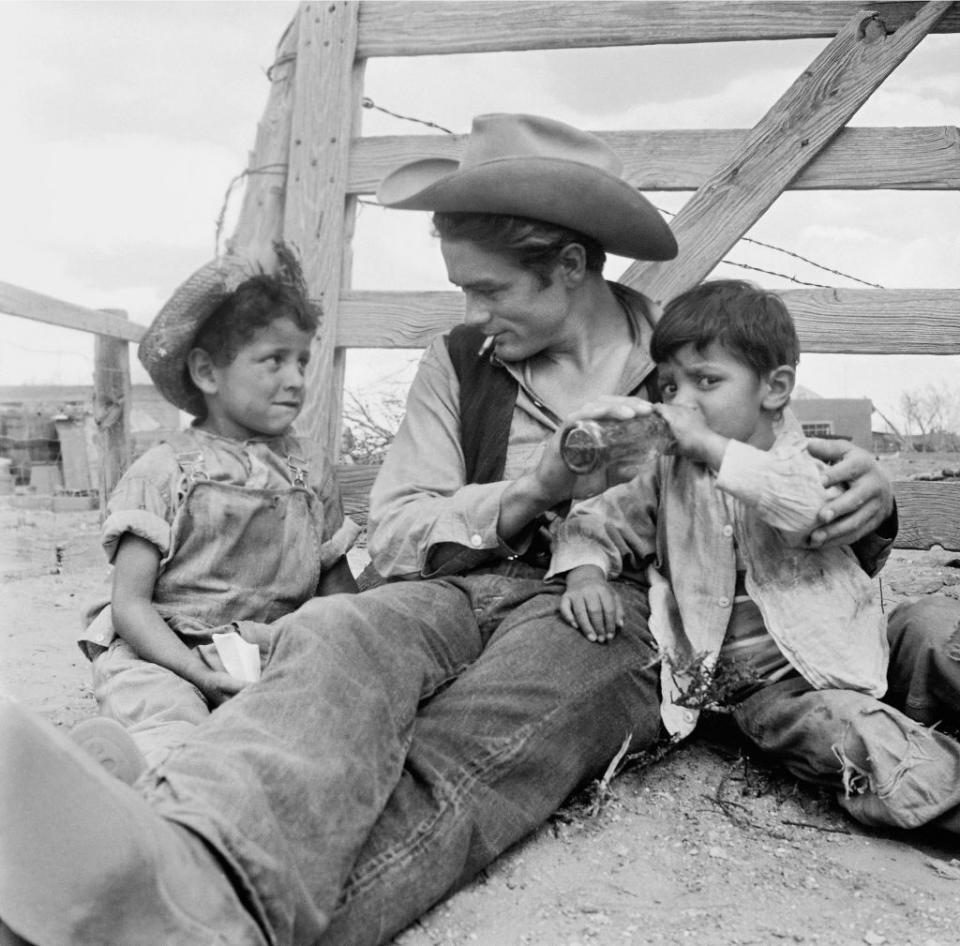 <p>Dean is seen tending to two small children while on set of <em>Giant. </em></p>