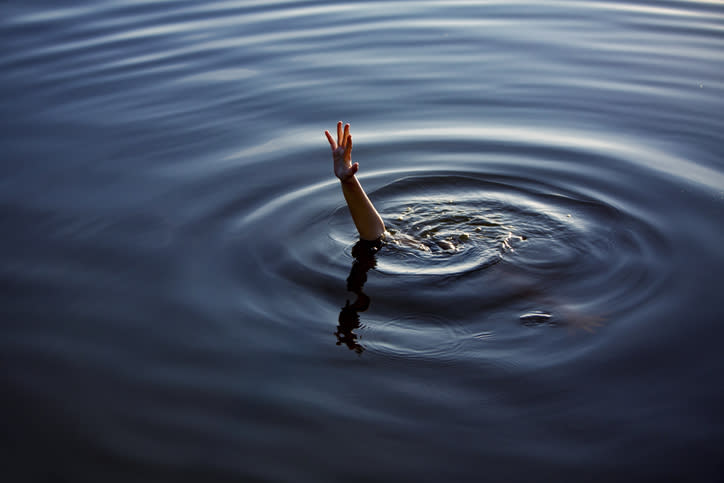 A hand is reaching out from the surface of a body of water, creating ripples. No text or other people are visible in the image