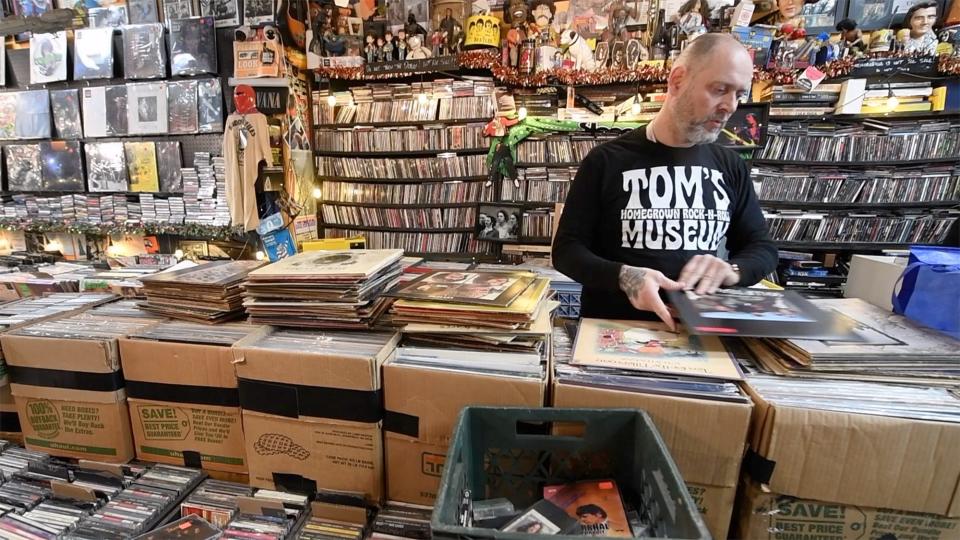 Tom Anderton sorts through vinyl records that he appraises while someone waits.