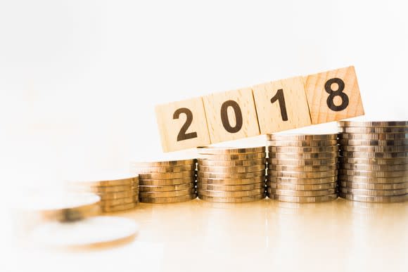 Wooden blocks with 2018 on top of ascending stacks of coins