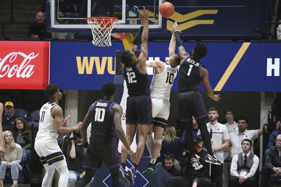 West Virginia guard Erik Stevenson (10) shoots between TCU forward Xavier Cork (12) and guard Mike Miles Jr. (1) during the first half of an NCAA college basketball game Wednesday, Jan. 18, 2023, in Morgantown, W.Va. (AP Photo/Kathleen Batten)