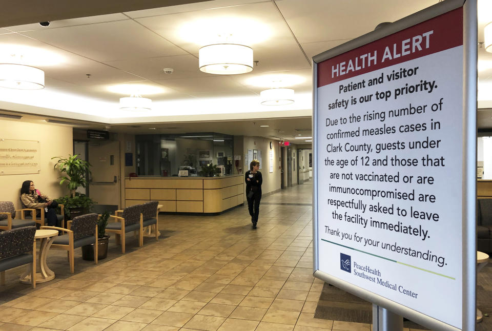 A sign prohibiting all children under 12 and unvaccinated adults stands at the entrance to PeaceHealth Southwest Medical Center in Vancouver, Wash., Friday, Jan. 25, 2019. Washington Gov. Jay Inslee declared a statewide public health emergency Friday as confirmed measles cases rose to 30, with nine more suspected. (AP Photo/Gillian Flaccus)