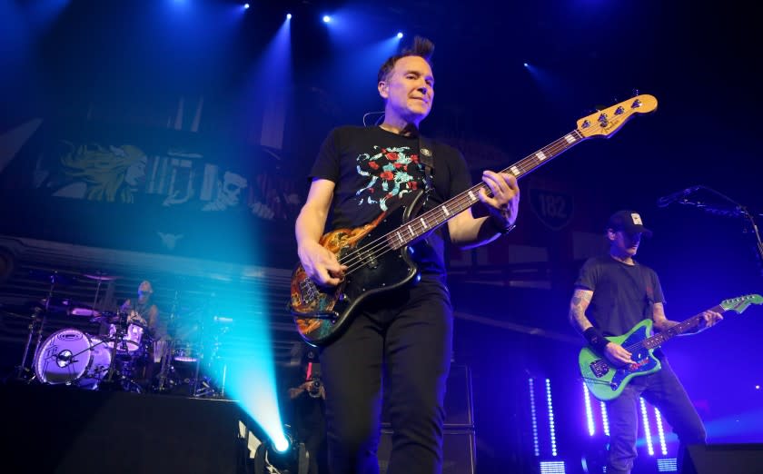 A man playing electric bass guitar on a stage with colorful lights