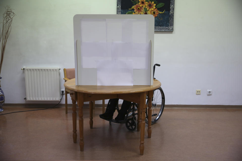 Olivia Bibe, 87, marks her presidential election ballot behind a makeshift voting booth at the elderly care home where she resides in Montijo, south of Lisbon, Tuesday, Jan. 19, 2021. For 48 hours from Tuesday, local council crews are collecting the votes from people in home quarantine and from residents of elderly care homes ahead of Sunday's presidential election. (AP Photo/Armando Franca)