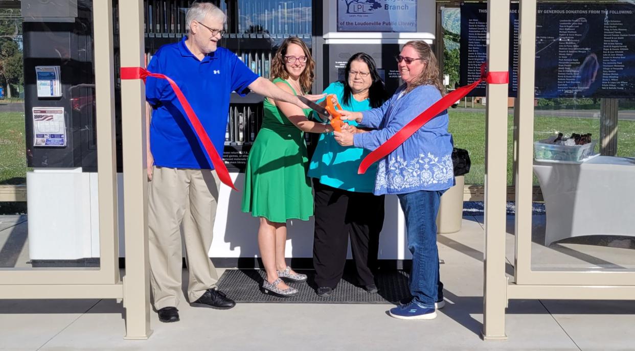 Armed with a hug pair of scissors loaned for the occasion by the Loudonville Chamber of Commerce, officials cut the ribbon for the new Perrysville branch of the Loudonville Public Library on Monday evening. June 27. Sharing in the cutting chore are, from left, Living Legacy Foundation President John Miller, Library Director Melissa Mallinak, Library Board President Peg Butler and Perrysville Mayor Heather Mullinnex.