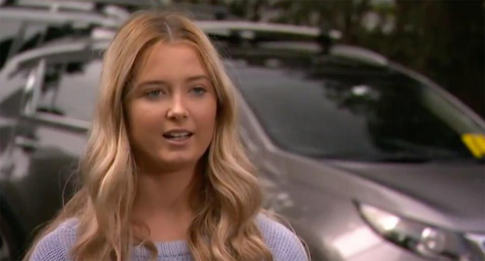 Hunter Reynolds stands in front of a car and speaks to a camera about her fine for ignoring social distancing. 