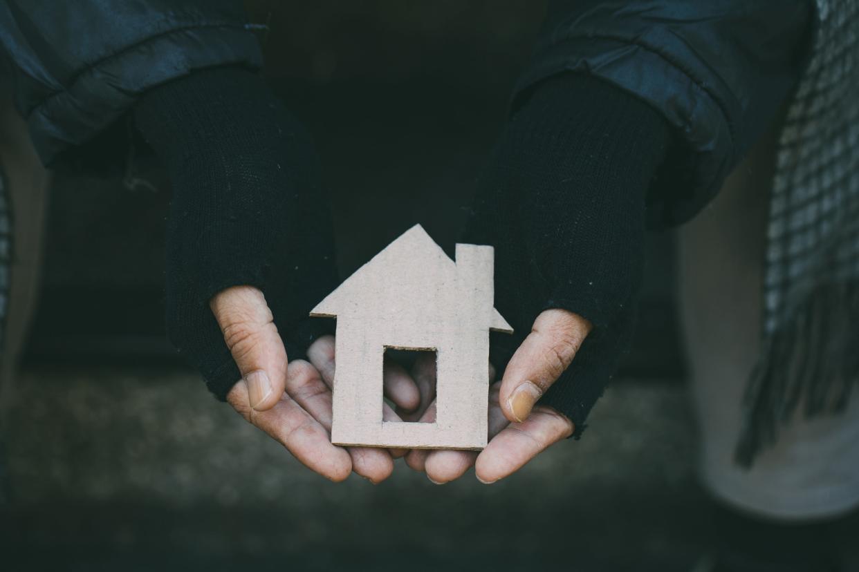 Poor tired depressed hungry homeless man holding a cardboard house. nostalgia and hope concept.