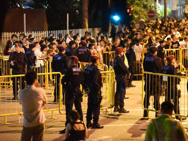 Police watch mourners waiting outside the parliament building, hoping to pay their last respects to former prime minister Lee Kuan Yew in Singapore late March 27, 2015