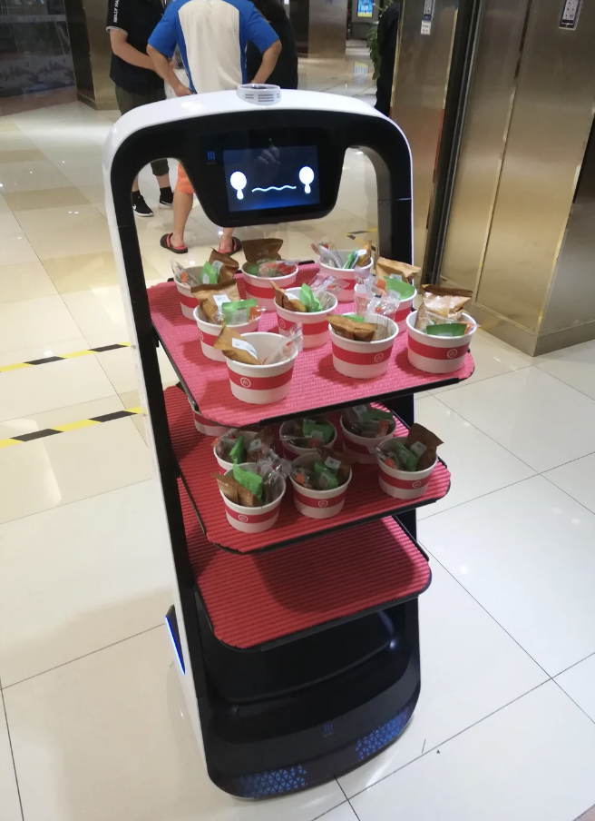 A service robot carrying multiple food trays in a mall