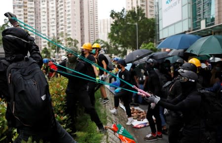 Anti-extradition bill protesters use a slingshot to hurl stones in front of a police station in Tseung Kwan O residential district, in Hong Kong