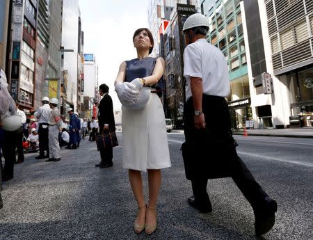 People wearing and holding helmets take part in a drill simulating a 7.2 magnitude earthquake in Tokyo, Japan, August 26, 2016. REUTERS/Kim Kyung-Hoon