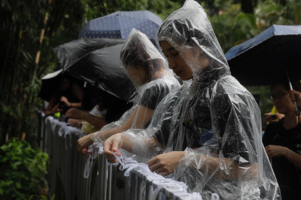 Pro-democracy protesters tie white-ribbons, symbolizing the pure intentions of young protesters during a march organized by teacher in Hong Kong Saturday, Aug. 17, 2019. China's paramilitary People's Armed Police marched and practiced crowd control tactics at a sports complex in Shenzhen across the border in Hong Kong on Friday, Aug. 16 in what some have interpreted as a threat against pro-democracy protesters. (AP Photo/Vincent Yu)