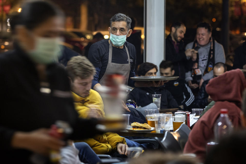 Waiters wearing masks serve food and drink in a terrace outside Mestalla stadium during the Champions League round of 16 second leg soccer match between Valencia and Atalanta in Valencia, Spain, Tuesday March 10, 2020. The match is being played in an empty stadium because of the coronavirus outbreak. (AP Photo/Emilio Morenatti)