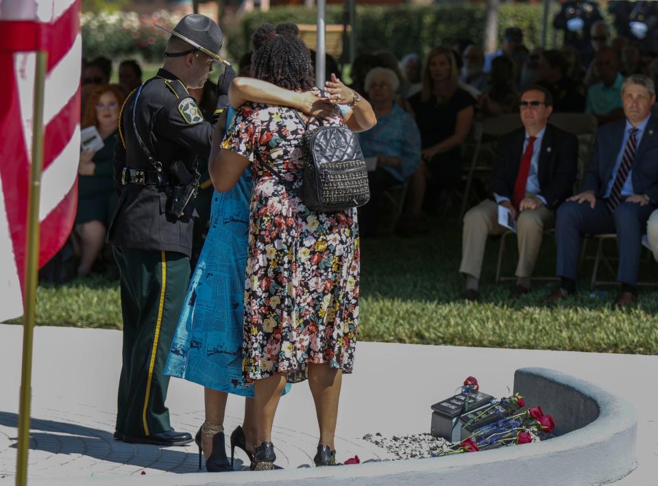 Family members of Polk County sheriff's Deputy Ronnie O'Neal Brown hug after laying a rose on his memorial plaque at the 34th annual Polk County Peace Officer Memorial service at Veterans Memorial Park in Lakeland on Thursday.