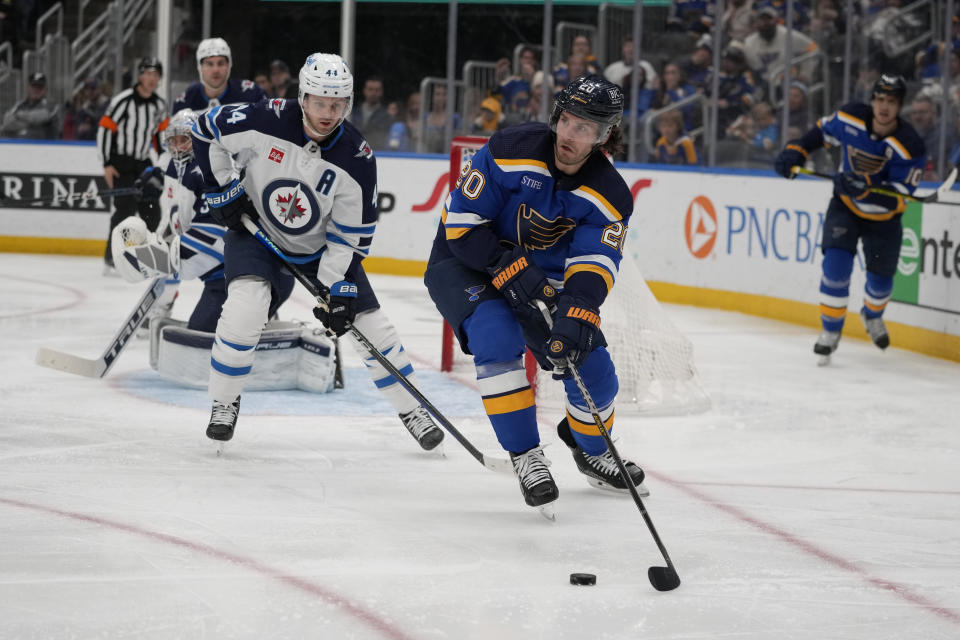 St. Louis Blues' Brandon Saad (20) looks to pass as Winnipeg Jets' Josh Morrissey (44) defends during the second period of an NHL hockey game Sunday, March 19, 2023, in St. Louis. (AP Photo/Jeff Roberson)