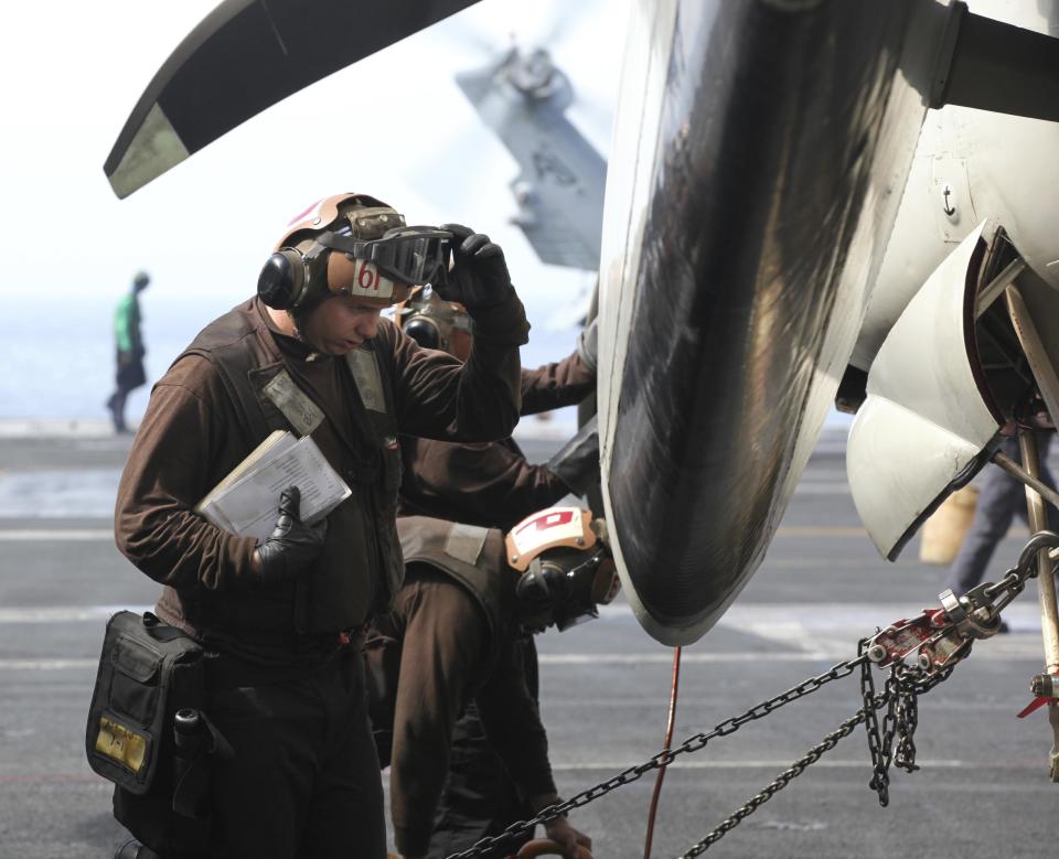 In this Monday, March 20, 2017 photograph, crew examine the propeller of an E-2C Hawkeye on the USS George H.W. Bush as it travels toward the Strait of Hormuz. The arrival of the nuclear-powered aircraft carrier to the Persian Gulf marks the first such deployment under new U.S. President Donald Trump. (AP Photo/Jon Gambrell)