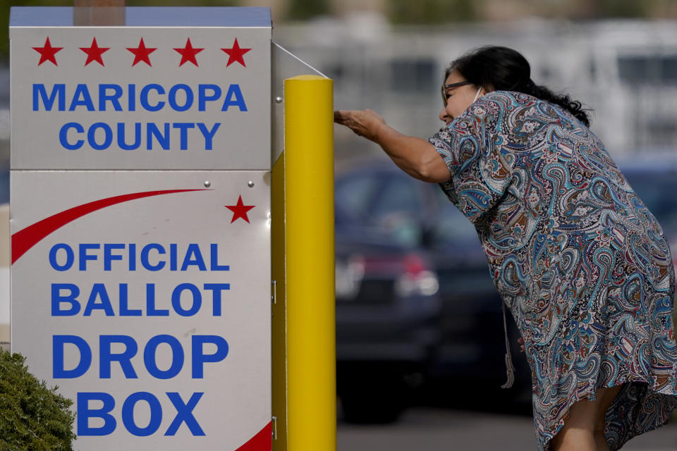 FILE - A voter drops off her ballot at a drop box, Nov. 7, 2022, in Mesa, Ariz. Republicans are re-evaluating their antipathy to mail voting. After former President Donald Trump condemned that method of casting ballots in 2020, conservatives shied away from it. That's given Democrats a multiweek jump on voting during elections. (AP Photo/Matt York, File)