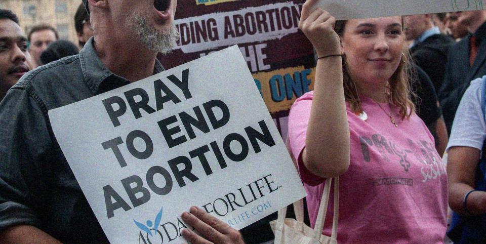 a man and woman holding a sign that protests against abortion