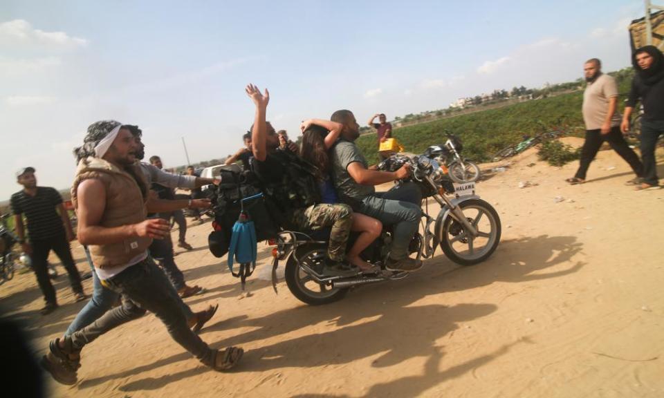 Militants transport a captured Israeli civilian from Kfar Azza kibbutz into the Gaza Strip