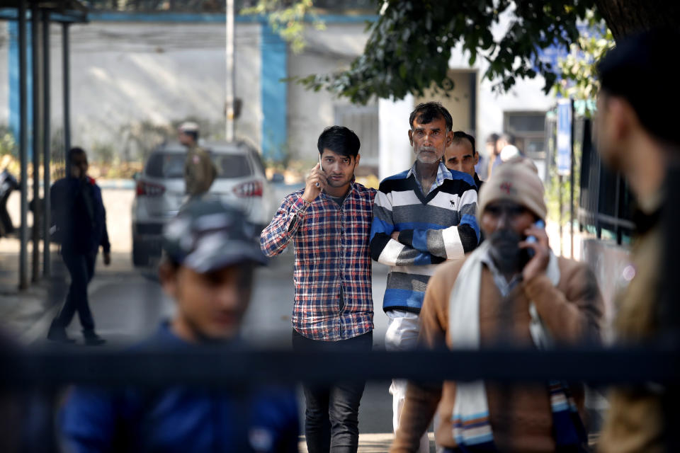 A family walks out from a mortuary after identifying the body of their relative who died in Sunday's fire in New Delhi, India, Monday, Dec. 9, 2019. Authorities say an electrical short circuit appears to have caused a devastating fire that killed dozens of people in a crowded market area in central New Delhi. Firefighters fought the blaze from 100 yards away because it broke out in one of the area's many alleyways, tangled in electrical wire and too narrow for vehicles to access. (AP Photo/Manish Swarup)