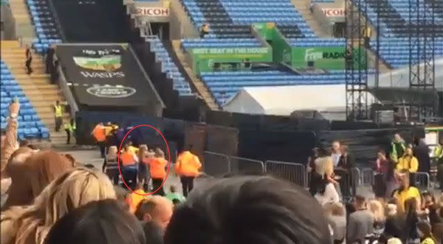 The woman is escorted out of the Ricoh Arena on Saturday, minutes before Rihanna was due to take the stage. Picture: Coventry Telegraph