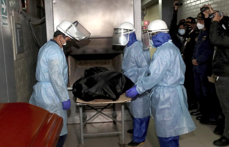 In this photo provided by Peru's Interior Ministry, crematorium workers place the body of Abimael Guzman, founder and leader of the Shining Path guerrilla movement, into an oven in Callao, Peru, Friday, Sept. 24, 2021. The Peruvian government cremated Guzman on Friday, according authorities. (Rolly Reyna/Peruvian Interior Ministry via AP)