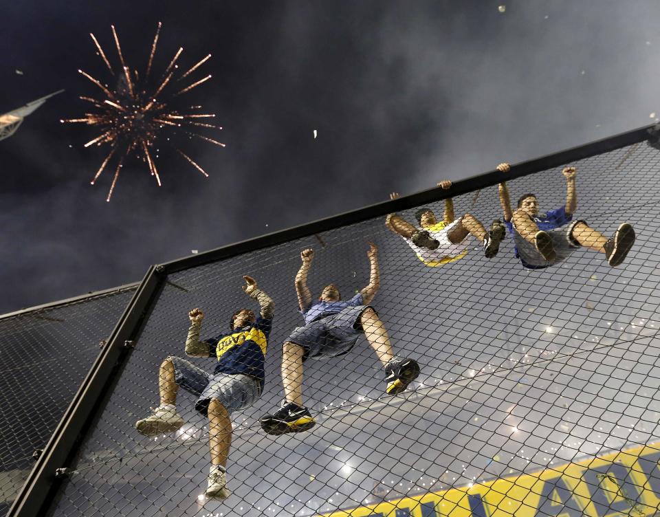 Boca Juniors fans climb a fence before the start of the Copa Sudamericana first round semi-final match against River Plate in Buenos Aires
