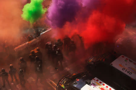 Separatist protesters throw coloured powder towards Mossos d'Esquadra police officers as they protest against a demonstration in support of the Spanish police units who took part in the operation to prevent an independence referendum in Catalonia on October 1, 2017, in Barcelona, Spain, September 29, 2018. REUTERS/Jon Nazca