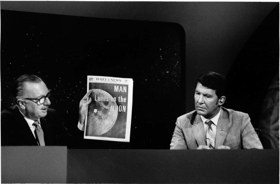 <div class="inline-image__caption"><p>TV news anchor Walter Cronkite (left) holds up a copy of the New York Daily News with a headline that read 'Man Lands on the Moon' during his coverage of NASA's Apollo 11 mission on July 20, 1969. Former astronaut Wally Schirra sat beside him.</p></div> <div class="inline-image__credit">CBS Photo Archive/Getty</div>