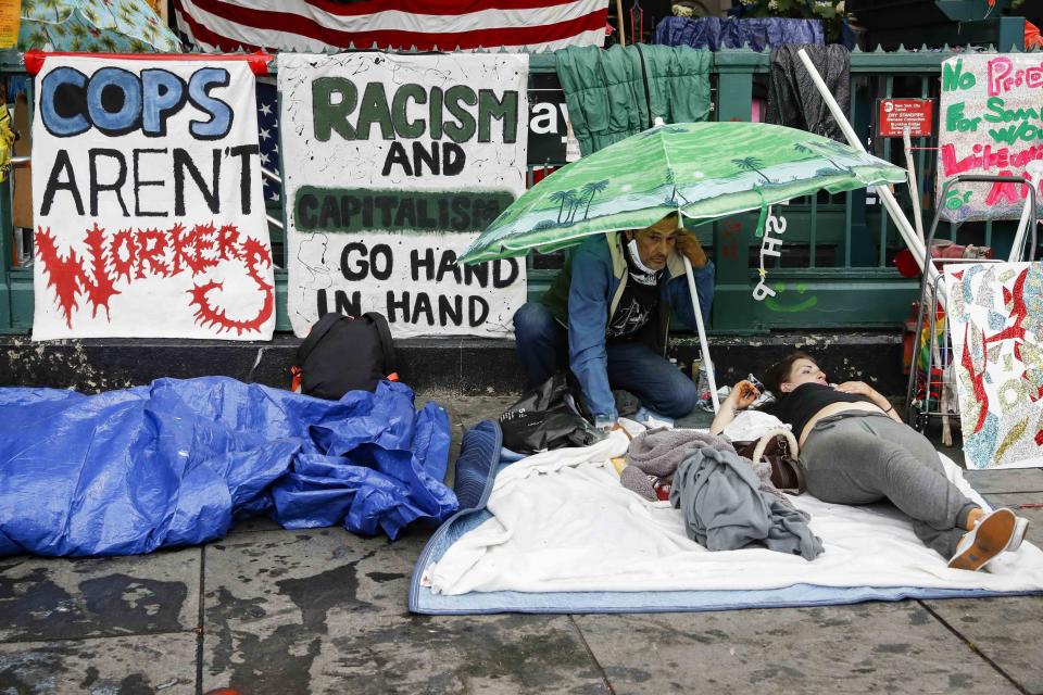 Protesters gather at an encampment outside City Hall, Tuesday, June 30, 2020, in New York. New York City lawmakers are holding a high-stakes debate on the city budget as activists demand a $1 billion shift from policing to social services and the city grapples with multibillion-dollar losses because of the coronavirus pandemic. (AP Photo/John Minchillo)