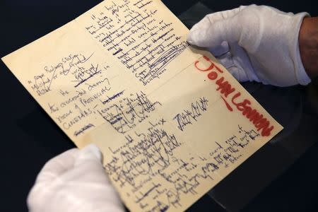 A Sotheby's employee handles a typescript signed by John Lennon during the press preview of a collection of Lennon's original drawings and manuscripts from 1964-65 at Sotheby's in New York May 29, 2014. REUTERS/Shannon Stapleton