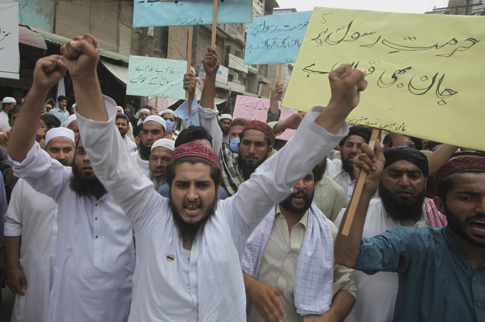 FILE - In this July 31, 2020 file photo, supporters of a religious group chant slogans with placards that read, "we can die for honor of Prophet" at a rally in Peshawar, Pakistan. Ali Hassan is in jail in Paris after allegedly attacking and seriously injuring two people with a meat cleaver in Paris on Sept. 25, 2020. Before the attack, he proclaimed in a video that he was seeking vengeance after the French satirical newspaper Charlie Hebdo republished caricatures of Islam’s Prophet Muhammad. In the video Hassan wept and said he had been inspired by teh Tehreek-e-Labbaik party, whose almost sole agenda is to uphold the blasphemy laws, which call for the death penalty against those who offend Islam. (AP Photo/Muhammad Sajjad, File)