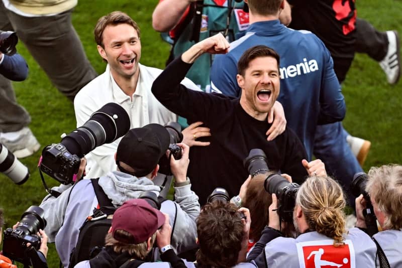 Leverkusen coach Xabi Alonso (R) and sporting director Simon Rolfes celebrate winning the German championship after the German Bundesliga soccer match between Bayer 04 Leverkusen and SV Werder Bremen, at BayArena. Bayer Leverkusen will play their first home game since players and fans took it to the pitch to celebrate the club's maiden Bundesliga title, and coach Xabi Alonso said that "the grass is good and playable." David Inderlied/dpa