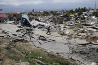 A man walks in Balaroa neighborhood which was flattened by Friday's earthquake in Palu, Central Sulawesi, Indonesia, Tuesday, Oct. 2, 2018. Home to hundreds of families, the neighborhood was once a patchwork of asphalted streets and tidy houses. Now it looks as if it was picked up and thrown back to earth with vicious force. Four days after the earthquake and tsunami hit the Indonesian city of Palu, this devastated neighborhood has received no government help and anger is simmering among its residents. (AP Photo/Dita Alangkara)