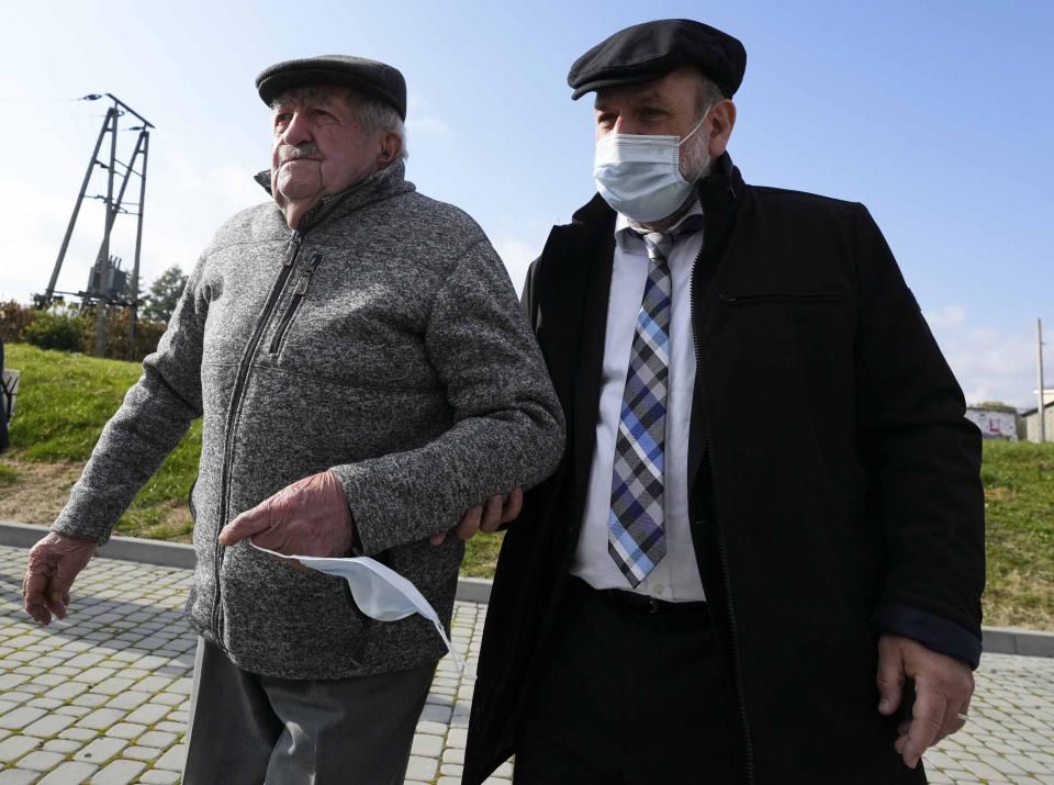 Poland's chief rabbi, Michael Schudrich, right, supports 94-year-old Boleslaw Sitarz, a witness to an execution by Nazi Germans of dozens of Jews during the Holocaust in Wojslawice, Poland, Thursday Oct. 14, 2021. On Thursday a grave was dedicated in Wojslawice to the victims, one of many in recent years to be discovered, secured and marked. (AP Photo/Czarek Sokolowski)