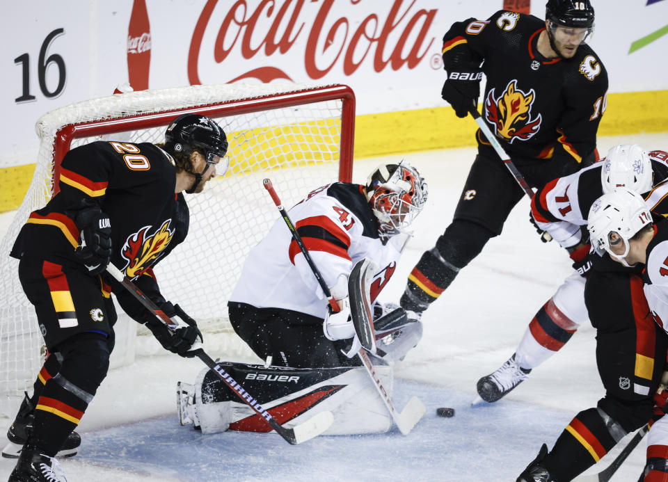 New Jersey Devils goalie Vitek Vanecek (41) defends the net as Calgary Flames forward Blake Coleman (20) and forward Jonathan Huberdeau, top right, try for rebounds during the first period of an NHL hockey match in Calgary, Alberta, Saturday, Dec. 9, 2023. (Jeff McIntosh/The Canadian Press via AP)