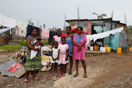 Marie Lestin (L), 34, poses for a photo next to her children in front of their new house after Hurricane Matthew hit Jeremie, Haiti. REUTERS/Carlos Garcia Rawlins