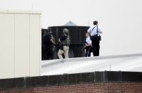 Law enforcement officers are deployed on a rooftop as they respond to a shooting on the base at the Navy Yard in Washington, September 16, 2013. The U.S. Navy said several people were injured and there were possible fatalities in the shooting at the Navy Yard in Washington D.C. on Monday. (REUTERS/Jason Reed)