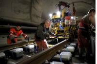 Workers use torque wrenches to fix screw nuts during the installation of the railway tracks in the NEAT Gotthard Base tunnel near Erstfeld May 7, 2012. Crossing the Alps, the world's longest train tunnel should become operational at the end of 2016. The project consists of two parallel single track tunnels, each of a length of 57 km (35 miles) REUTERS/Arnd Wiegmann