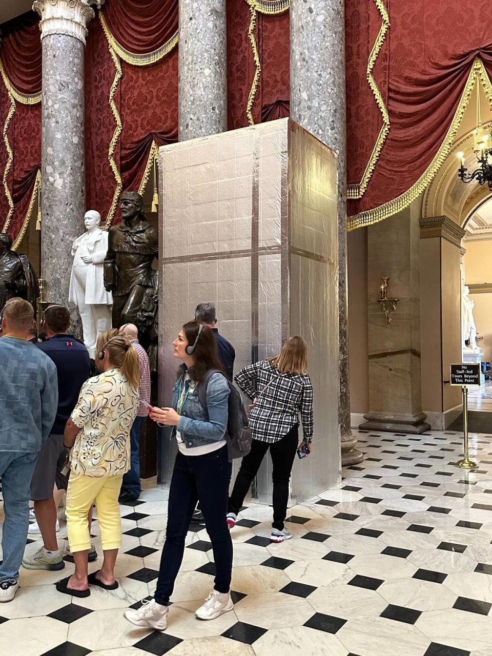 Tourists look at a box hiding the soon-to-be unveiled statue of the Rev. Billy Graham in Statuary Hall, in the Capitol, on May 11, 2024.