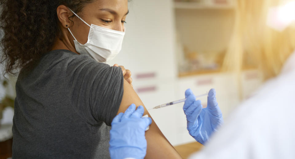 A woman wearing a mask receives an injection.